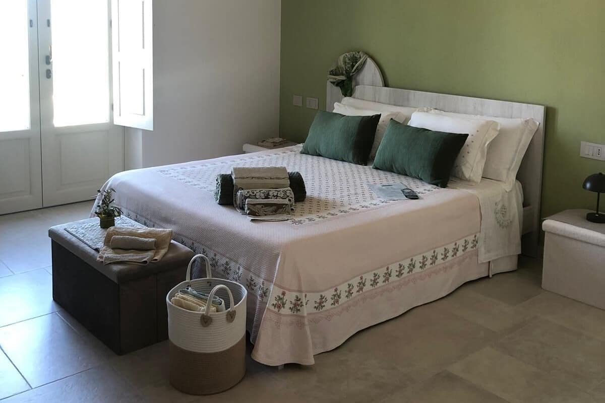 A bedroom with a large bed, green walls, and a rustic ceiling.