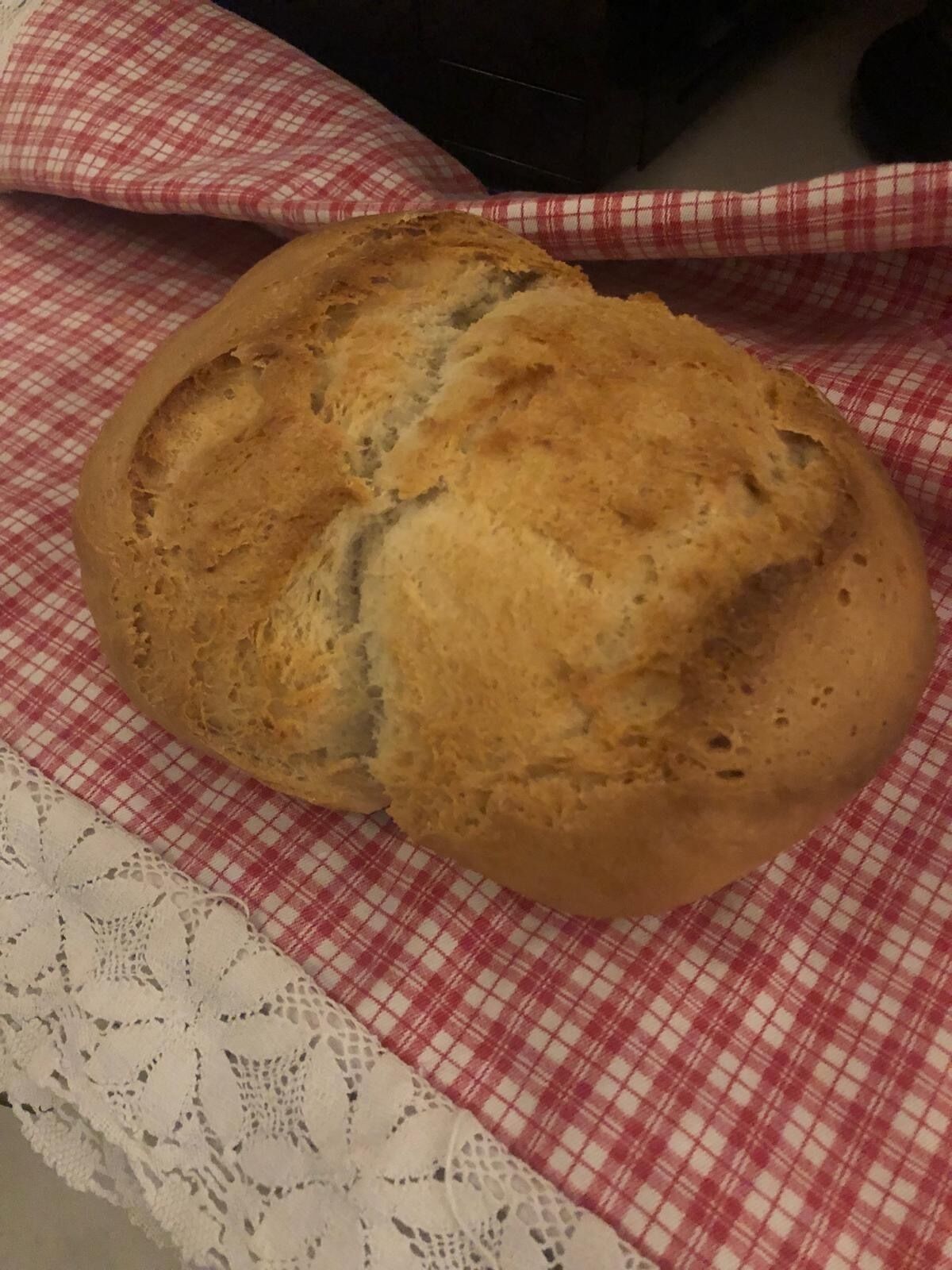 Une miche de pain posée sur une nappe à carreaux rouges et blancs.