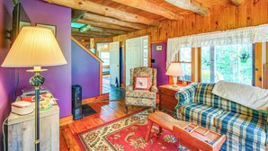 Una habitación acogedora con vigas de madera, un sofá a cuadros, una silla y un escritorio con lámpara.