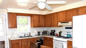 Una cocina con armarios de madera, un refrigerador blanco, una estufa y una mesa de comedor con sillas.