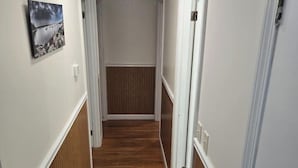 Un pasillo estrecho con suelo de madera y paredes blancas.