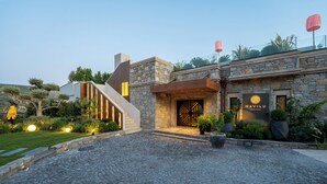 A modern building with a stone facade, a wooden staircase, and a well-lit entrance. - Mavilu Luxury Hotel (Bodrum)