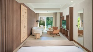 A modern hotel room with a large bed, a seating area with a sofa and chairs, a TV, and a large window offering a view of the outdoors. - Mavilu Luxury Hotel (Bodrum)