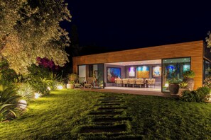 Un bâtiment moderne doté d’un espace extérieur bien éclairé, d’une façade en verre et d’un jardin aménagé.