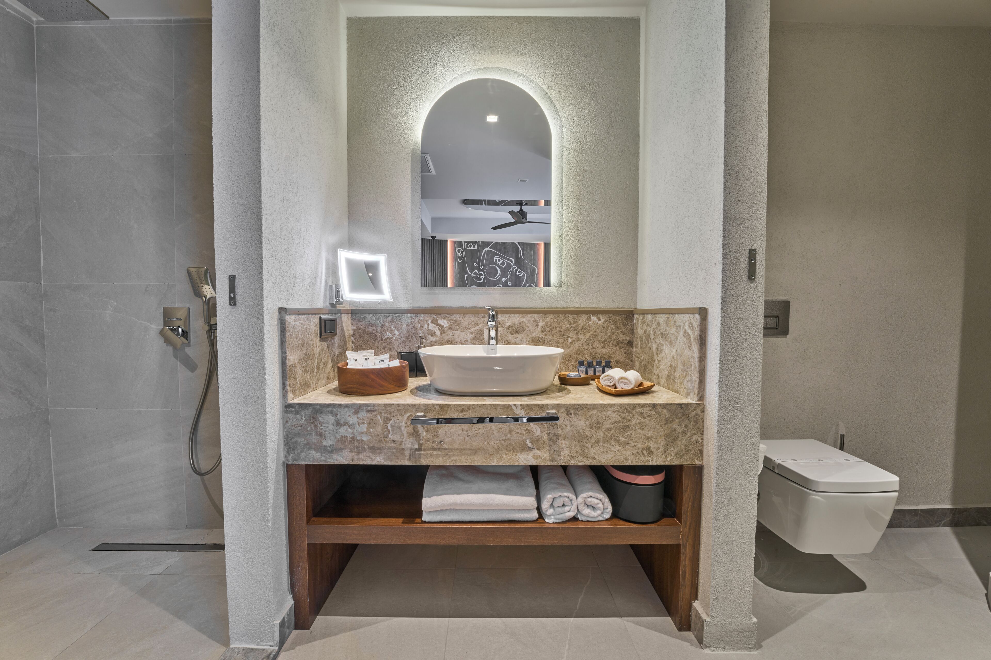 Un baño moderno con un lavamanos independiente, un espejo con marco arqueado y una zona de ducha.