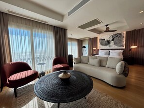 A modern hotel room with a sofa, two armchairs, a round coffee table, and a large abstract painting on the wall. - Mavilu Luxury Hotel (Bodrum)