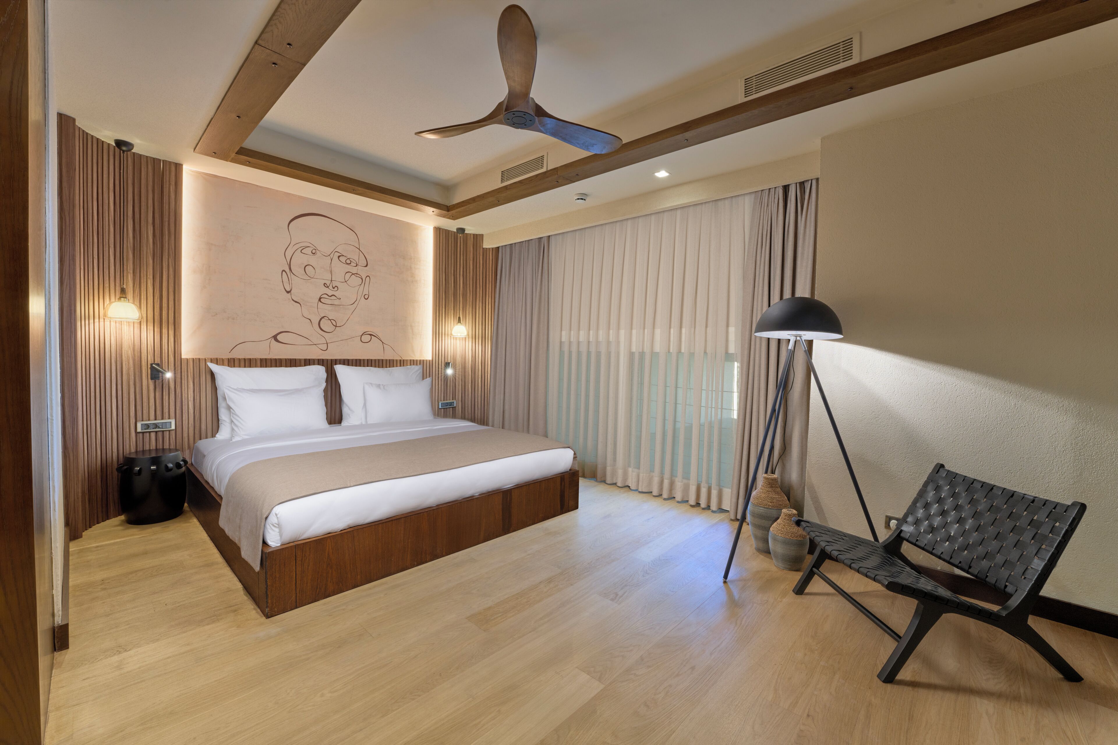 Un dormitorio moderno con una cama grande, un ventilador de techo y un banco junto a la ventana.