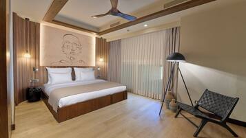 Un dormitorio moderno con una cama grande, un ventilador de techo y un banco junto a la ventana.
