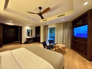 Una habitación de hotel con cama, escritorio, silla, televisor y ventilador de techo.
