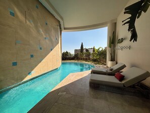 Un área junto a la piscina con una silla de descanso y una planta en maceta.
