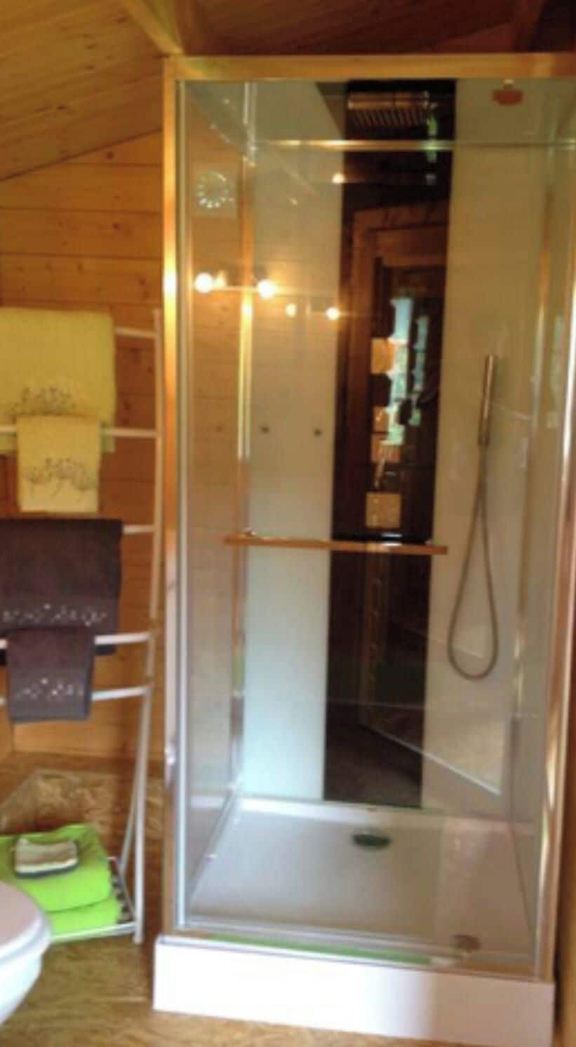 A glass-enclosed shower stall with a showerhead and a towel rack to the left.