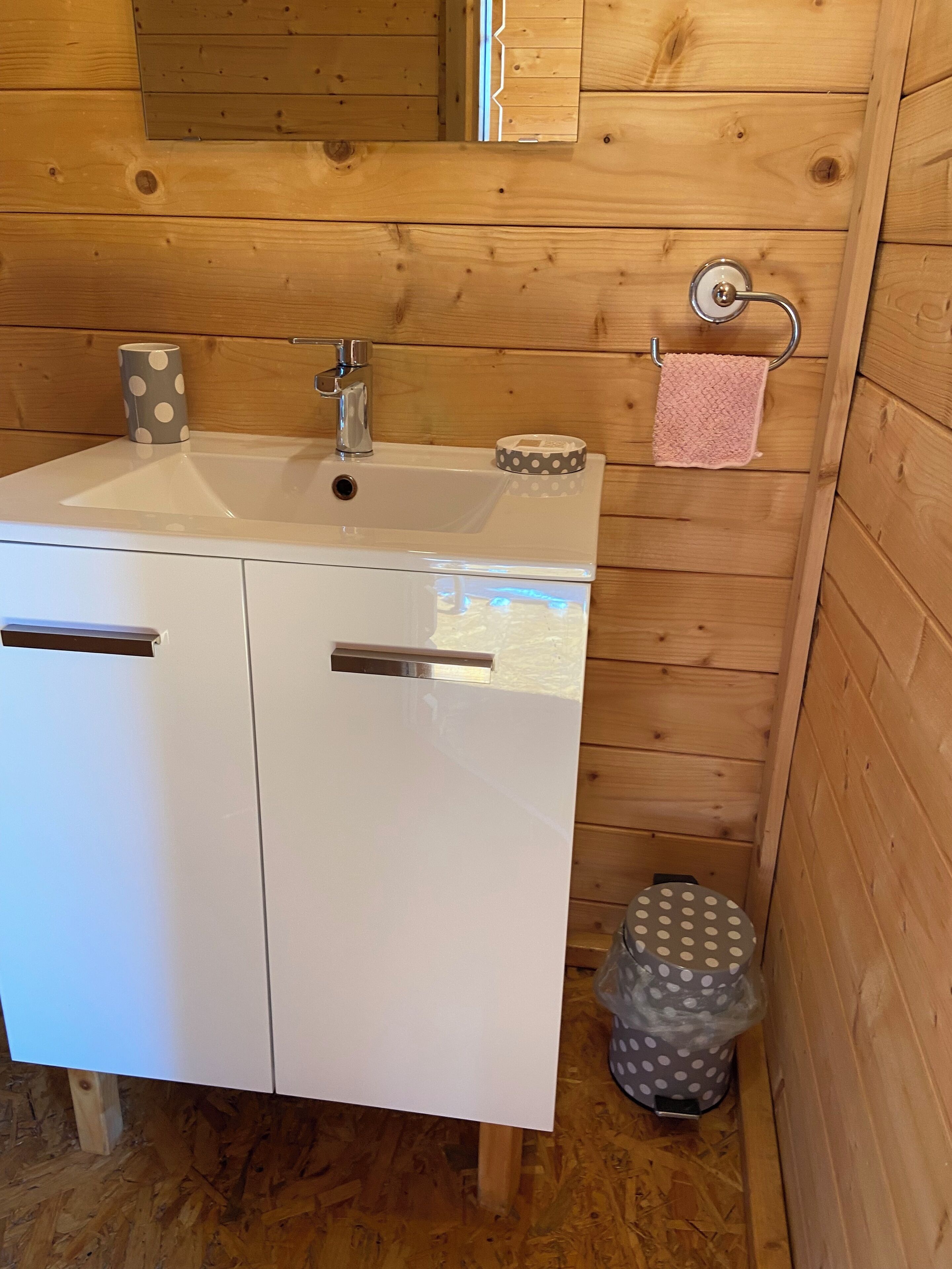 Een badkamer met een wit wastafel, een spiegel en een houten vloer.