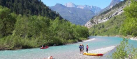 A river with kayaks and a group of people near the shore.
