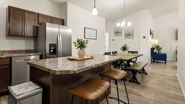 Une cuisine moderne dotée de plans de travail en granit, d’appareils électroménagers en acier inoxydable et d’armoires en bois.