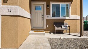 Un bâtiment de couleur beige, avec une porte blanche, une fenêtre et le chiffre « 13 » peint sur le mur.