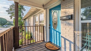 A wooden porch with a blue door, a mailbox, and a doormat.