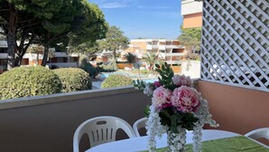 A balcony with a table set for two, overlooking a pool and a building complex. - Flat with terrace overlooking the pool (Bibione)