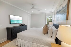 Ein Schlafzimmer mit einem Bett, einem Schminktisch, einem Deckenventilator und einem Bild an der Wand.