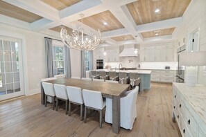 A spacious kitchen with a central island, white cabinetry, and a chandelier.