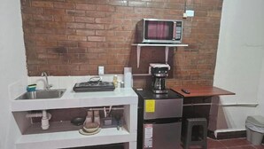 Eine kleine Küchenzeile mit Spüle, Mikrowelle, Kaffeemaschine und kleinem Kühlschrank.