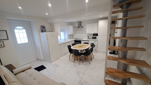 A modern kitchen with white cabinets, a dining area with a table and chairs, and a staircase with wooden steps. - Gite des moissons 41 near Chambord castle  (La Chapelle-Saint-Martin-en-Plaine)
