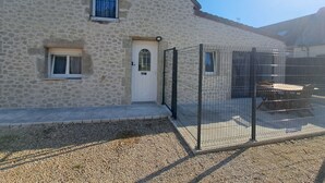 A stone building with a white door, a small window with a curtain, and a fenced outdoor area. - Gite des moissons 41 near Chambord castle  (La Chapelle-Saint-Martin-en-Plaine)