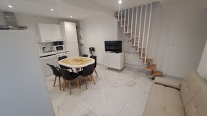 A modern kitchen with white cabinets, a dining table with chairs, a sofa, and a staircase. - Gite des moissons 41 near Chambord castle  (La Chapelle-Saint-Martin-en-Plaine)