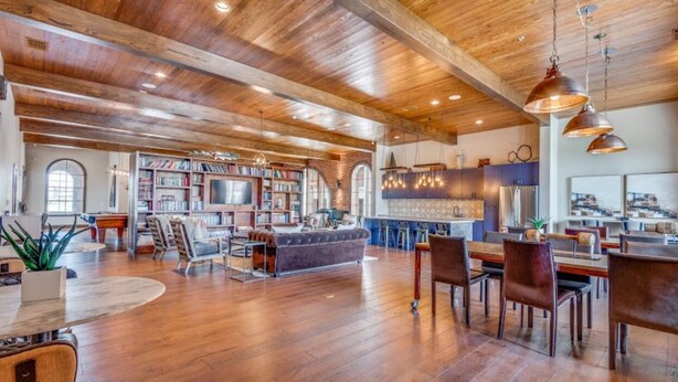 Ein geräumiger Wohnbereich mit Holzboden, einem Kamin und einem großen Bücherregal.