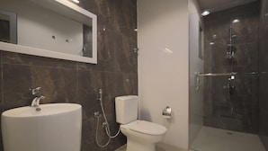 A modern bathroom with a large sink, toilet, and glass-enclosed shower.