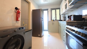 Une cuisine moderne équipée d’un lave-linge, d’un réfrigérateur et d’une cuisinière.