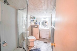 Ein kleines Badezimmer mit Duschkabine, Toilette und Waschtisch mit Spiegel.