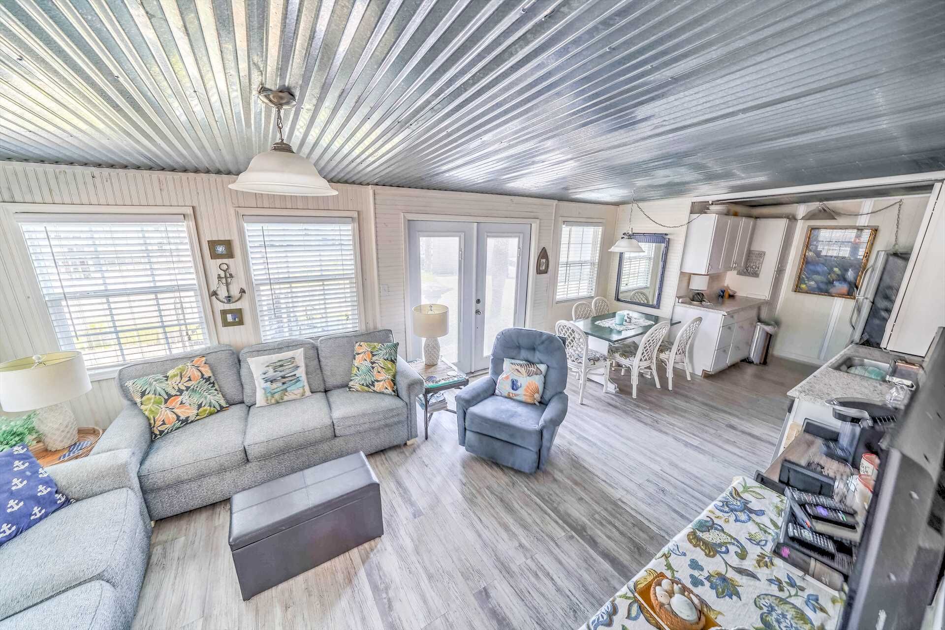 A spacious living area with a gray sofa, a blue armchair, and a dining table with chairs.
