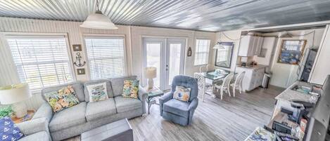 A spacious living area with a gray sofa, a blue armchair, and a dining table with chairs.