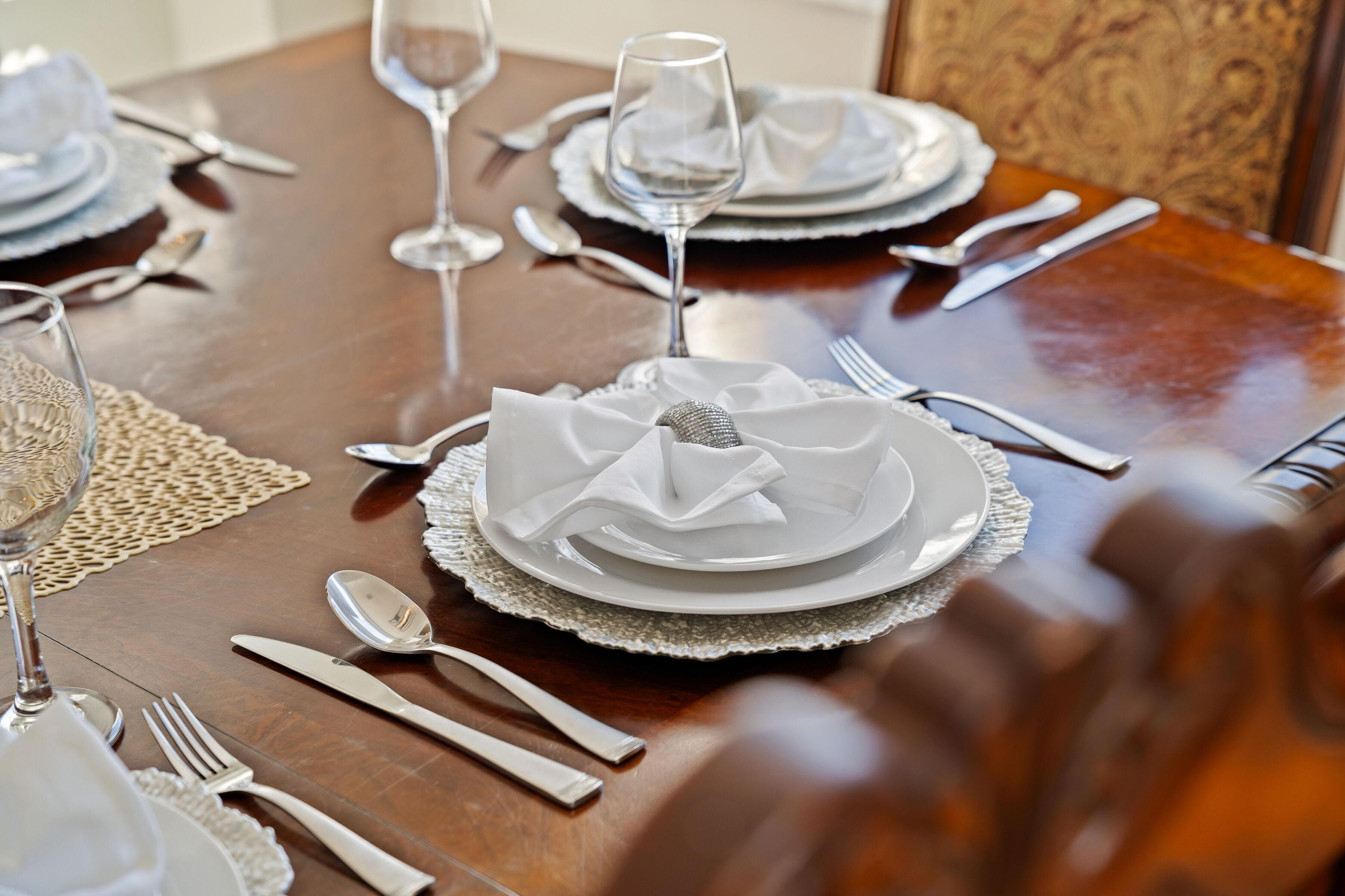 Mesa lista para comer con platos blancos, cubiertos y un vaso de agua.