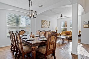 A dining area with a wooden table set for six, surrounded by ornate chairs.