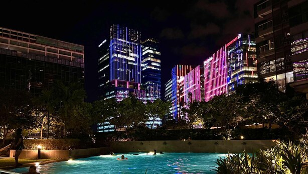 A nighttime pool area with a view of illuminated skyscrapers in the background.