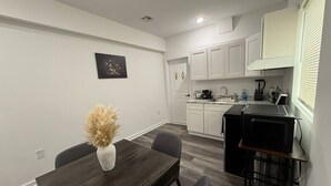 A modern kitchen with white cabinets, a granite countertop, and a black refrigerator.