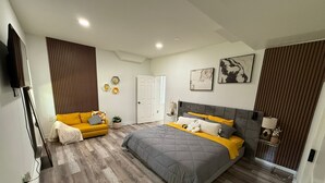 A modern bedroom with a bed, a sofa, and a television.