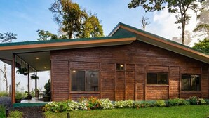 Une maison moderne en bois, dotée d’un porche abrité, de grandes fenêtres et d’un jardin bien entretenu.