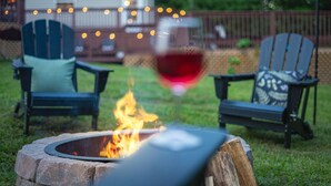 Ein Garten mit Feuerstelle, zwei Adirondack-Stühlen und einer Lichterkette.