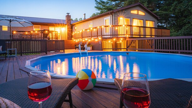 Ein Swimmingpool mit Holzterrasse, Liegestühlen und einem Strandball.