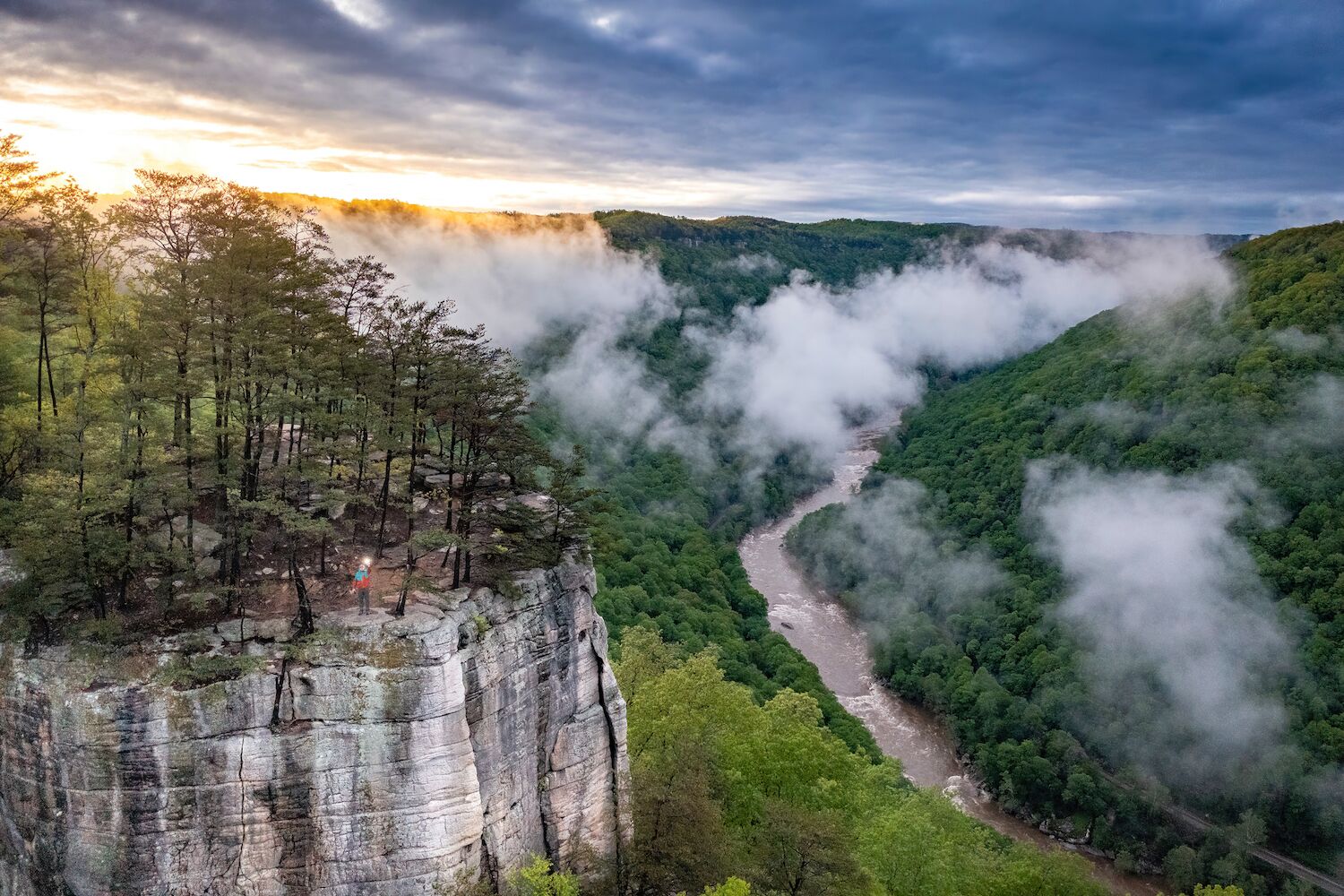 A river winding through a forested valley with a rocky cliff on the left.