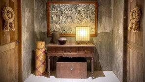 Una habitación con un mural grande, un escritorio de madera con cajones, una lámpara y dos cestas decorativas.