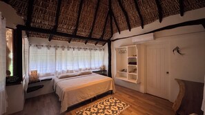 A cozy bedroom with a bed, a built-in shelf, a window with curtains, and a thatched roof. - Arena Negra (Santa María Tonameca)