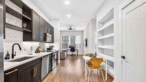 A modern kitchen with dark cabinets, a white countertop, and a dining area with a table and chairs. - Stylish 1BR in Heart of Midtown Tampa (Tampa)