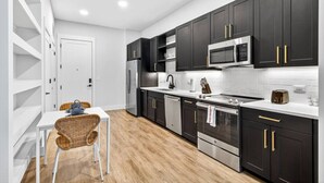 A modern kitchen with dark cabinets, stainless steel appliances, and a white countertop. - Stylish 1BR in Heart of Midtown Tampa (Tampa)