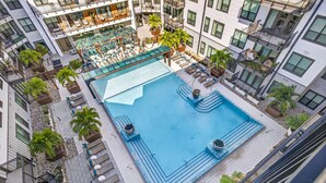 An aerial view of a modern hotel with a central swimming pool, multiple balconies, and outdoor seating areas. - Stylish 1BR in Heart of Midtown Tampa (Tampa)