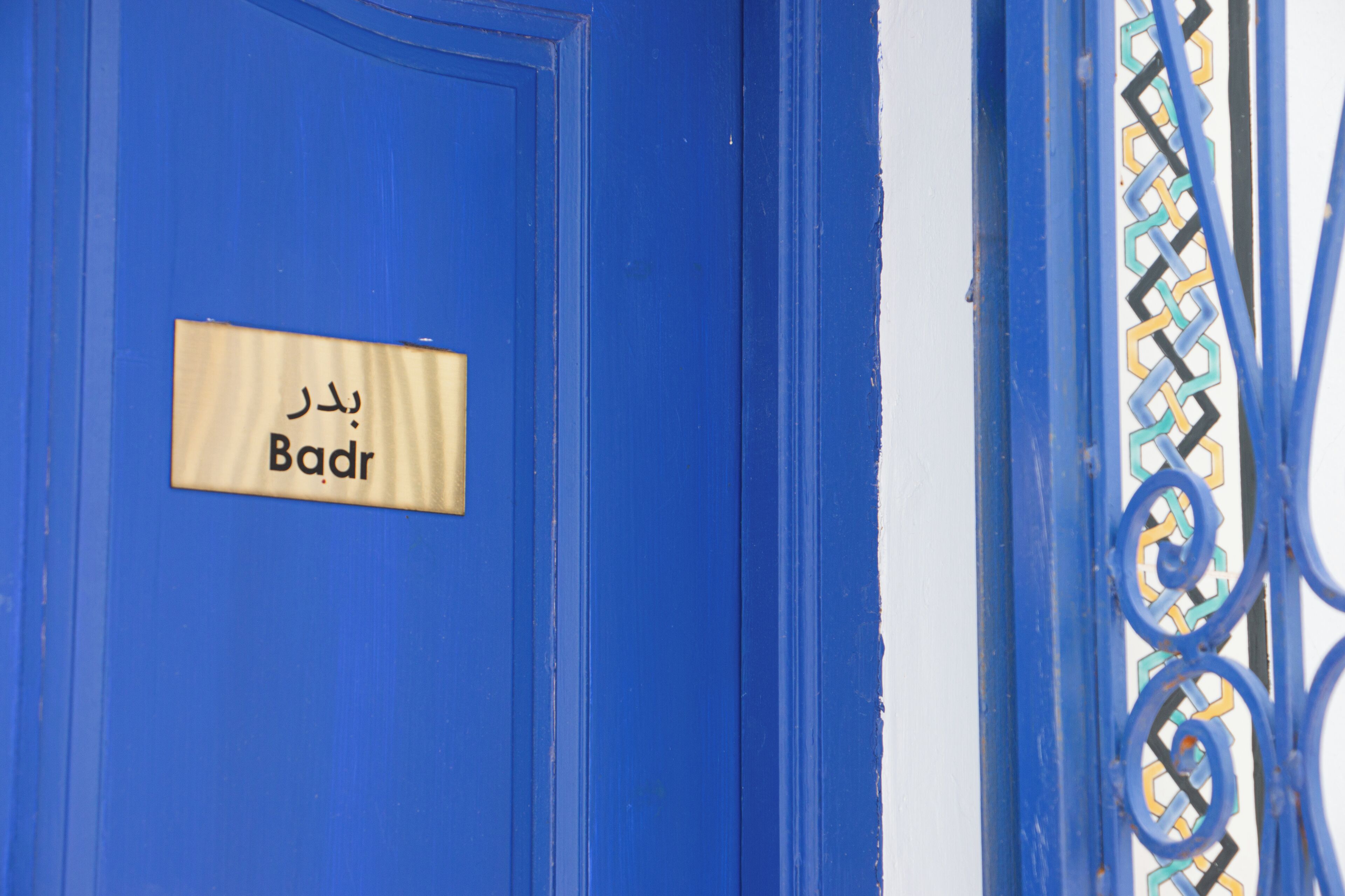 A blue door with a sign that reads 'Badr' in Arabic.