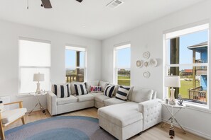 Un salon moderne avec un canapé d’angle, une petite table et une grande fenêtre donnant sur un beau paysage.