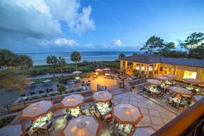 Un espace extérieur aménagé pour les repas, avec des parasols et des tables donnant sur la plage.
